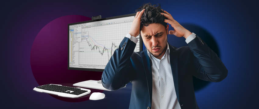 A stressed man in a suit holds his head in front of a computer screen while working on a forex trading analysis.